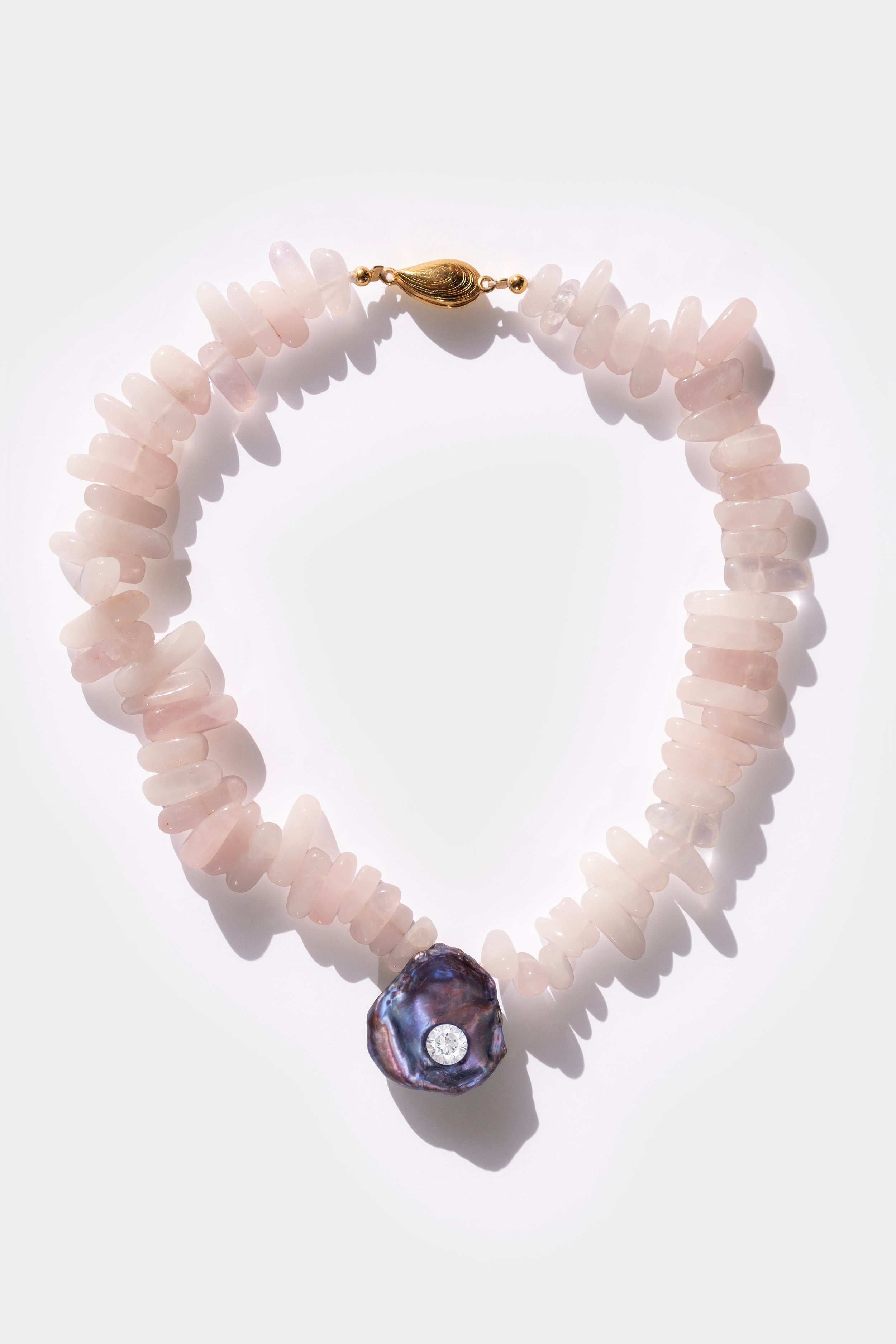 Necklace with pink quartz stones and a purple black keshi pearl and white cubic zirconia crystal gemstone on a white background