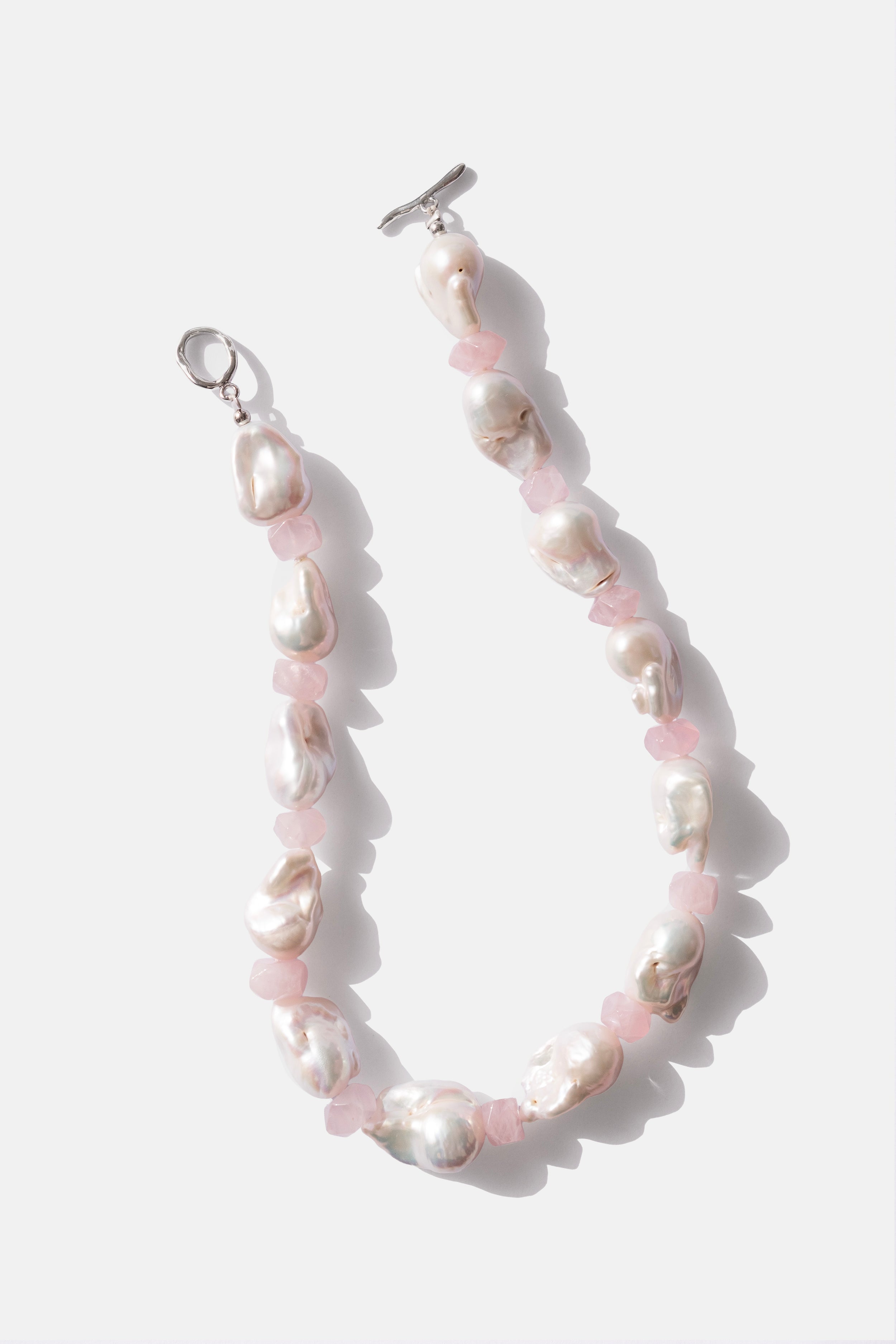 Pearl necklace with silver clasp and pink rose quartz beads on a white background