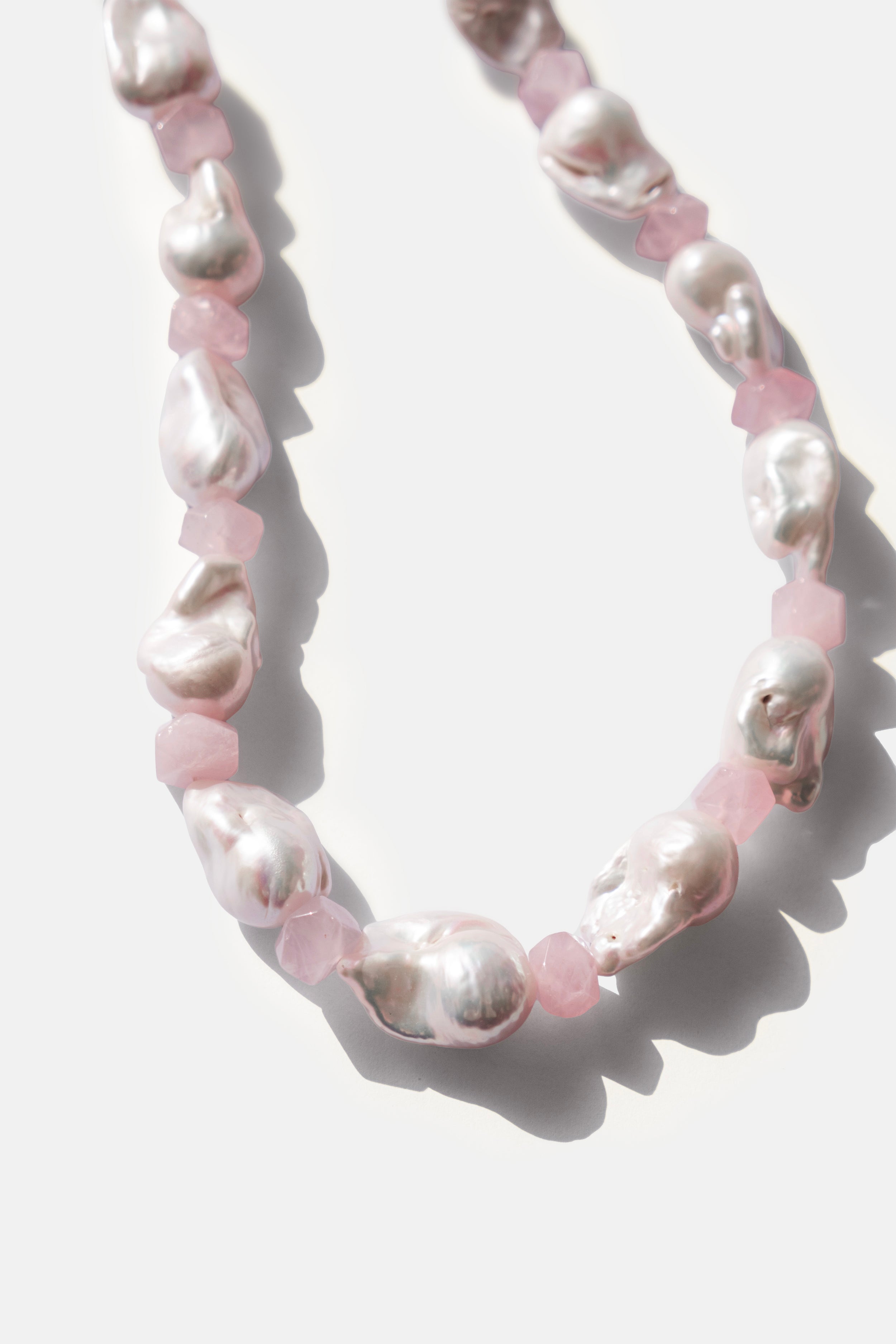 Necklace with pink rose quartz beads and white pearls on a light background