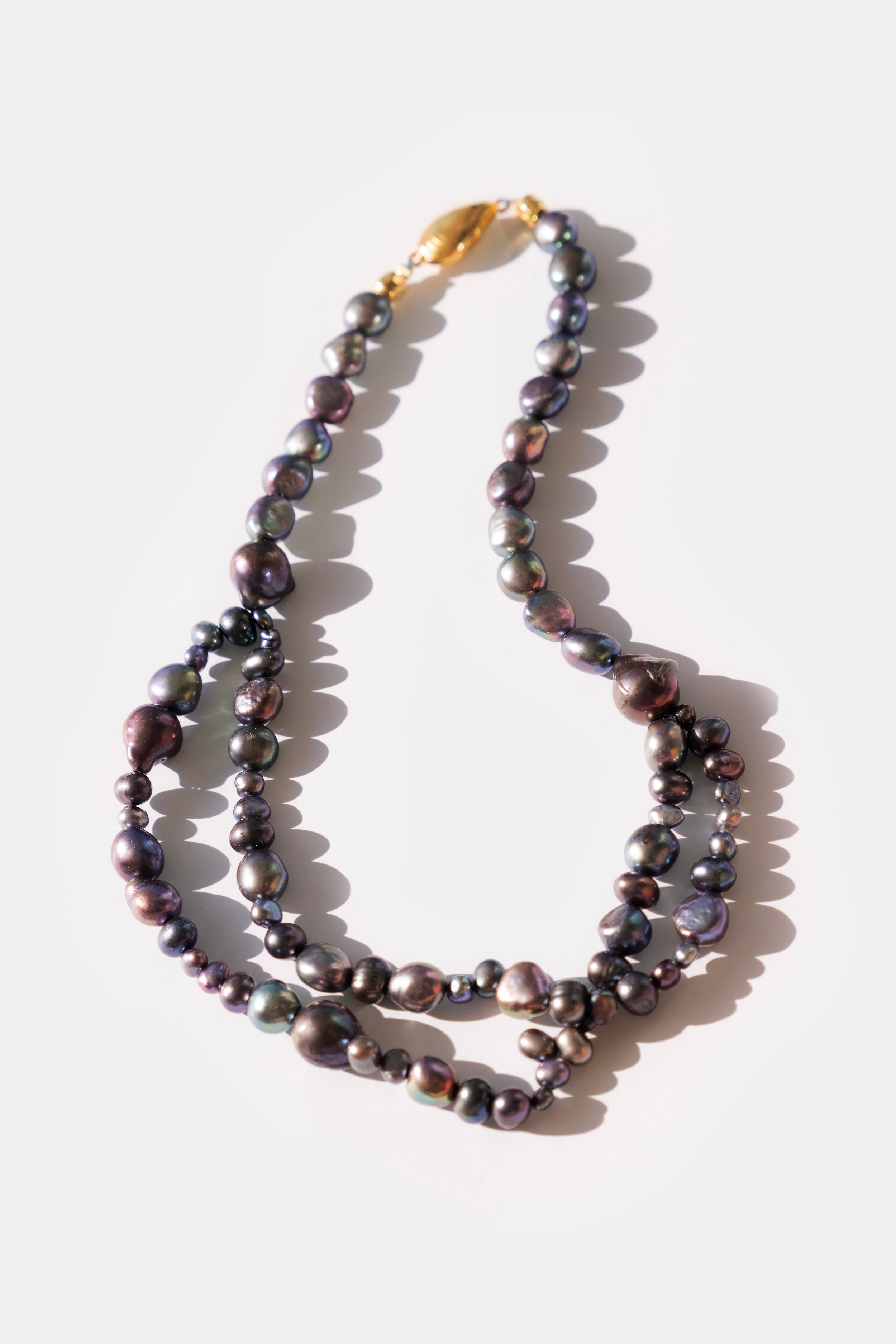 Black Pearl necklace with a gold clasp on a white background