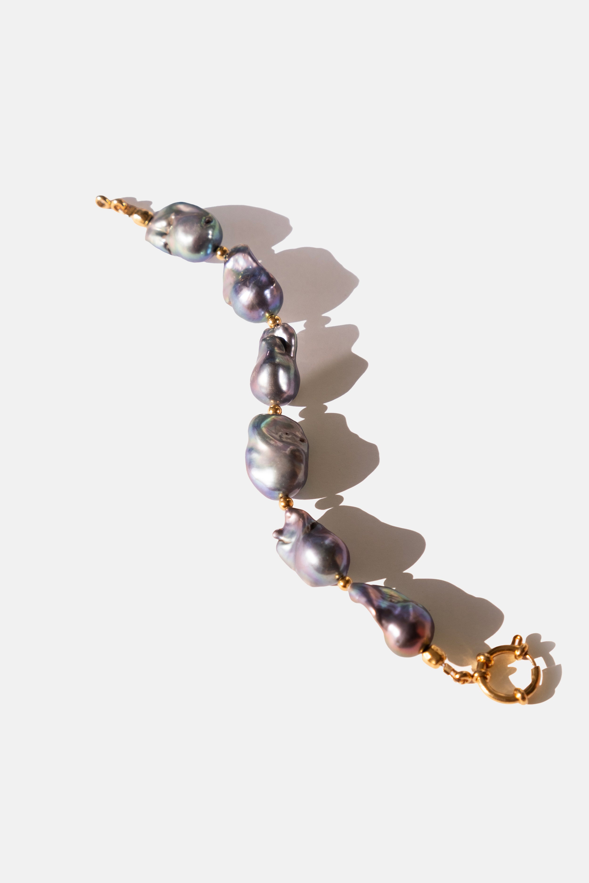 Pearl bracelet with gold clasp on a white background