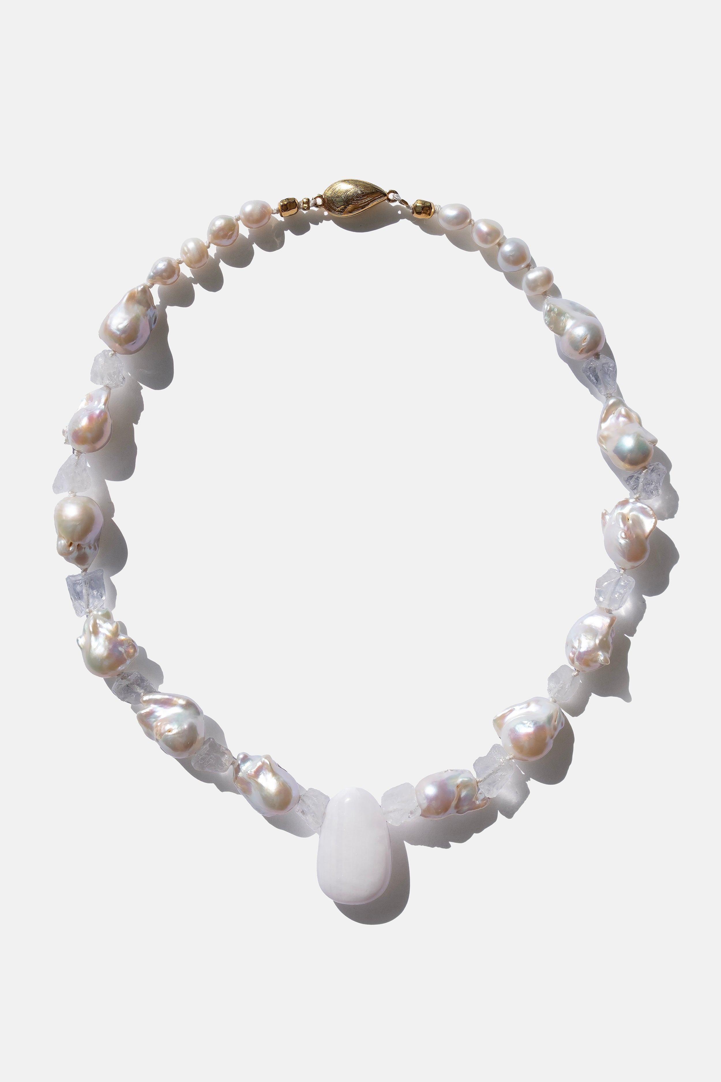 Pearl necklace with a central white stone on a light gray background