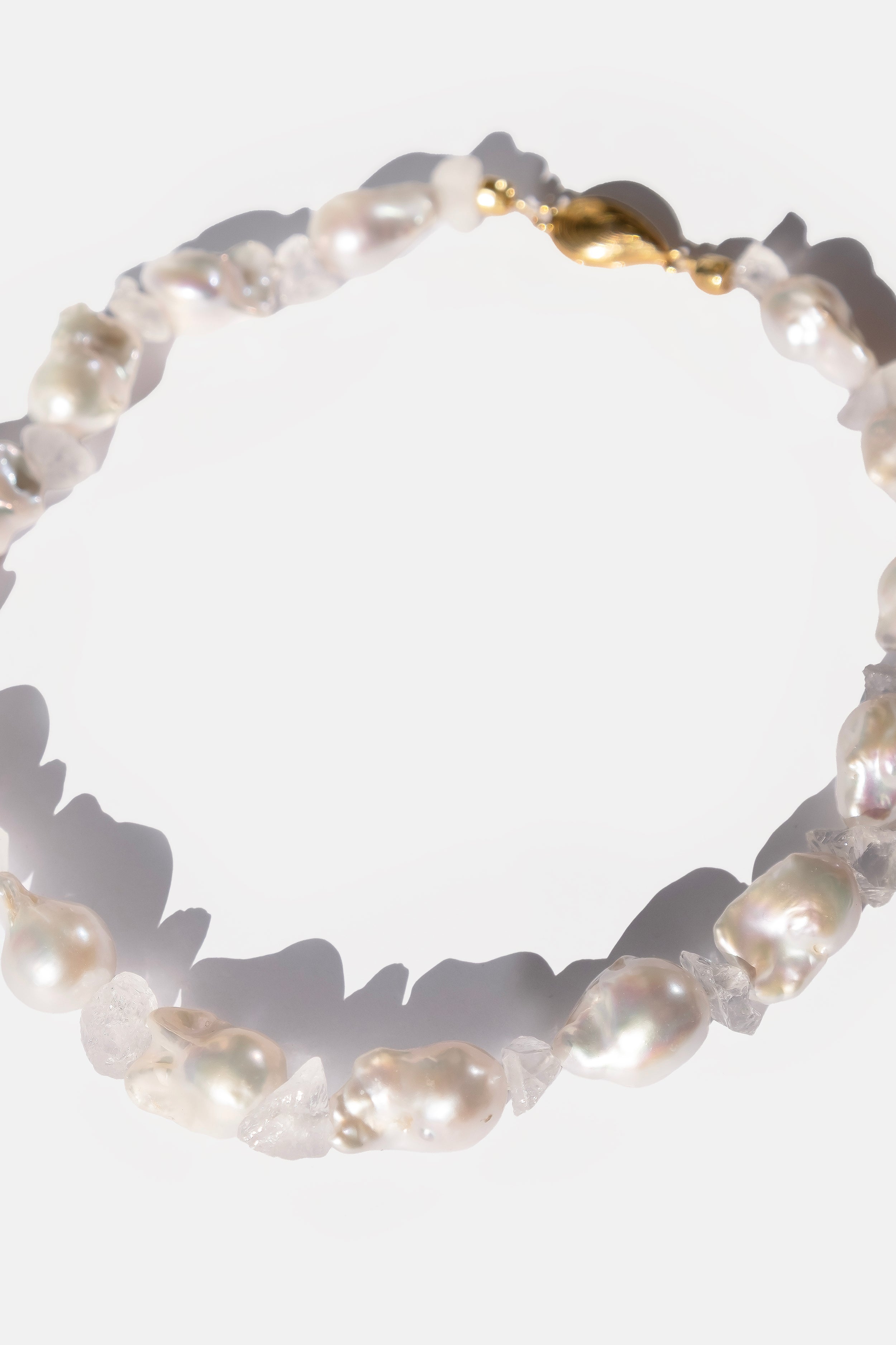 Pearl necklace with gold clasp on a white background