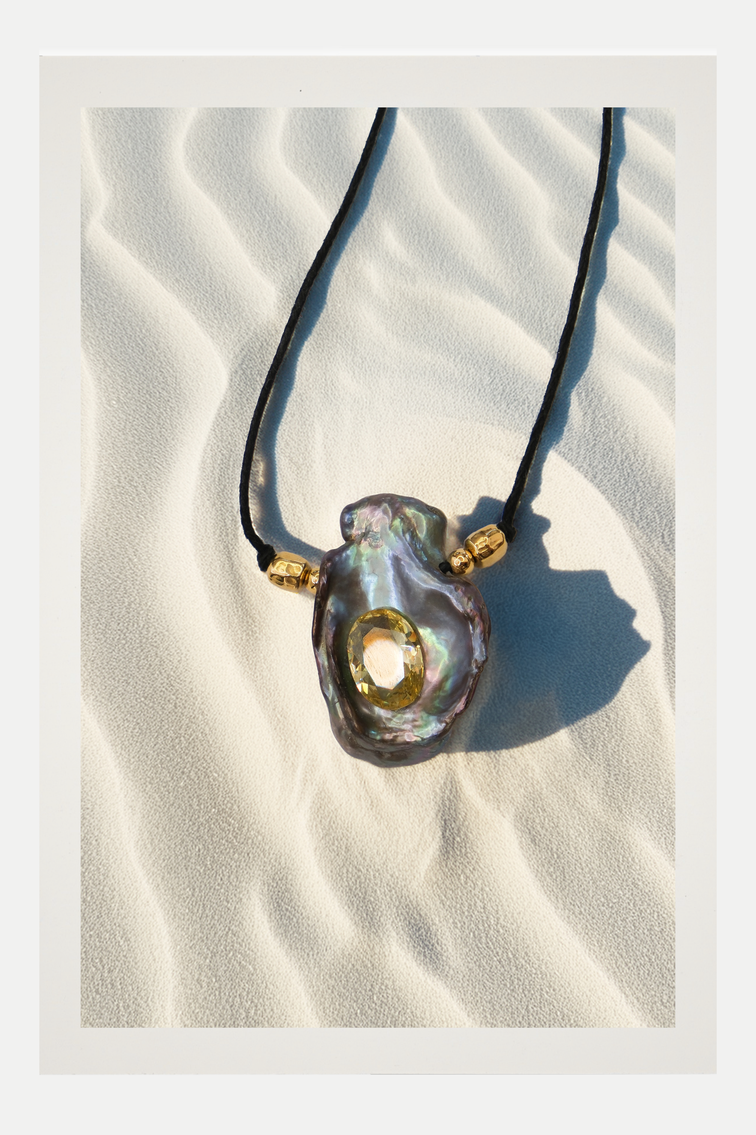 Necklace with a large, black pearl multicolored pendant on a textured white surface