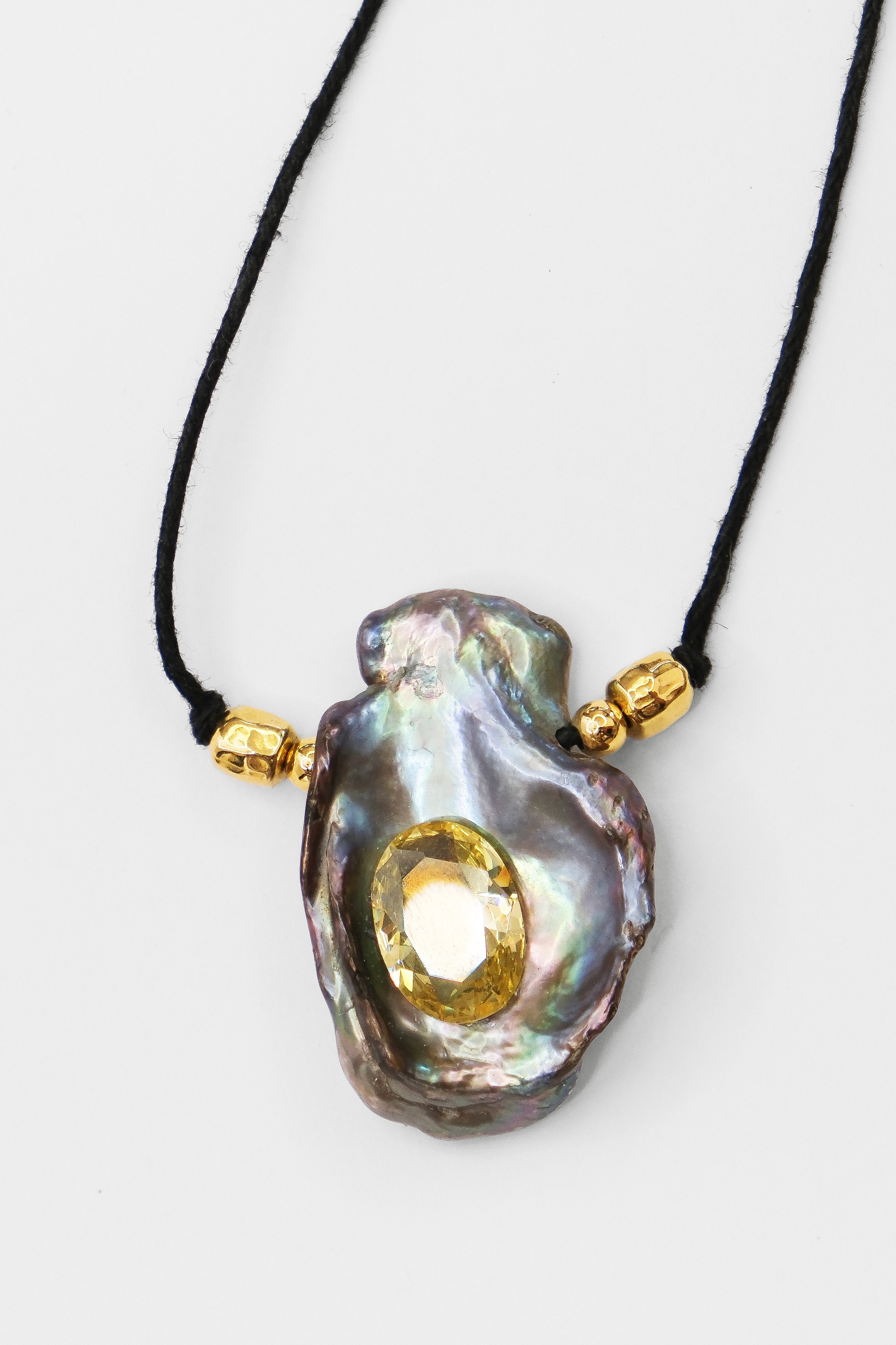 Necklace with a large black keshi pearl pendant and gold accents on a white background